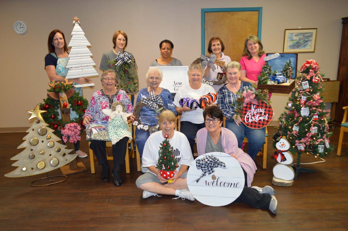 Several ladies pose for a photo with the crafts they made for the annual Christmas Bazaar. 