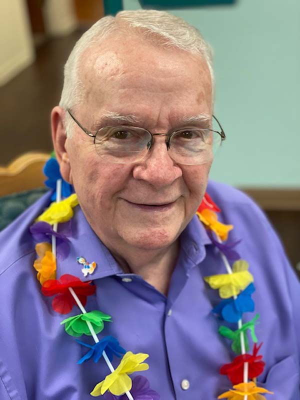 Tim, a client at NTC, smiles for the camera while wearing a lei necklace.